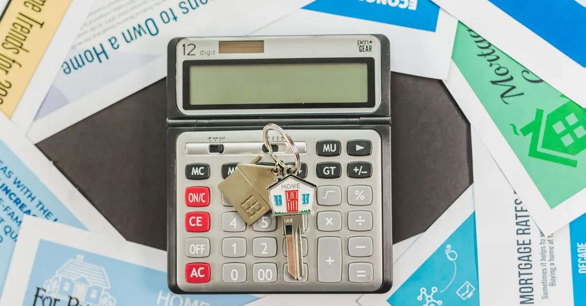 Calculadora, llave y maqueta de casa sobre una mesa, representando el presupuesto de una reforma de baño